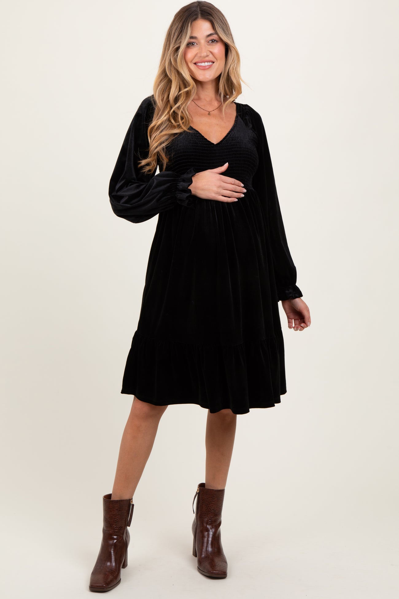 woman wearing a black velvet maternity dress with a v-neck and long sleeves, showing her baby bump