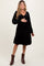 woman wearing a black velvet maternity dress with a v-neck and long sleeves, showing her baby bump