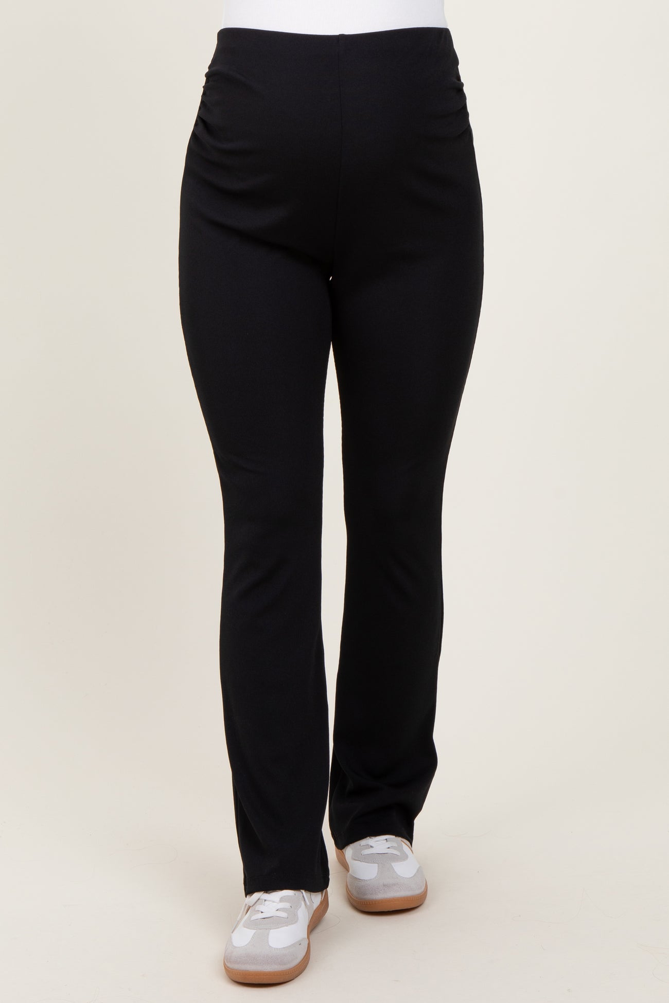 woman wearing black maternity leggings with side ruching and white sneakers