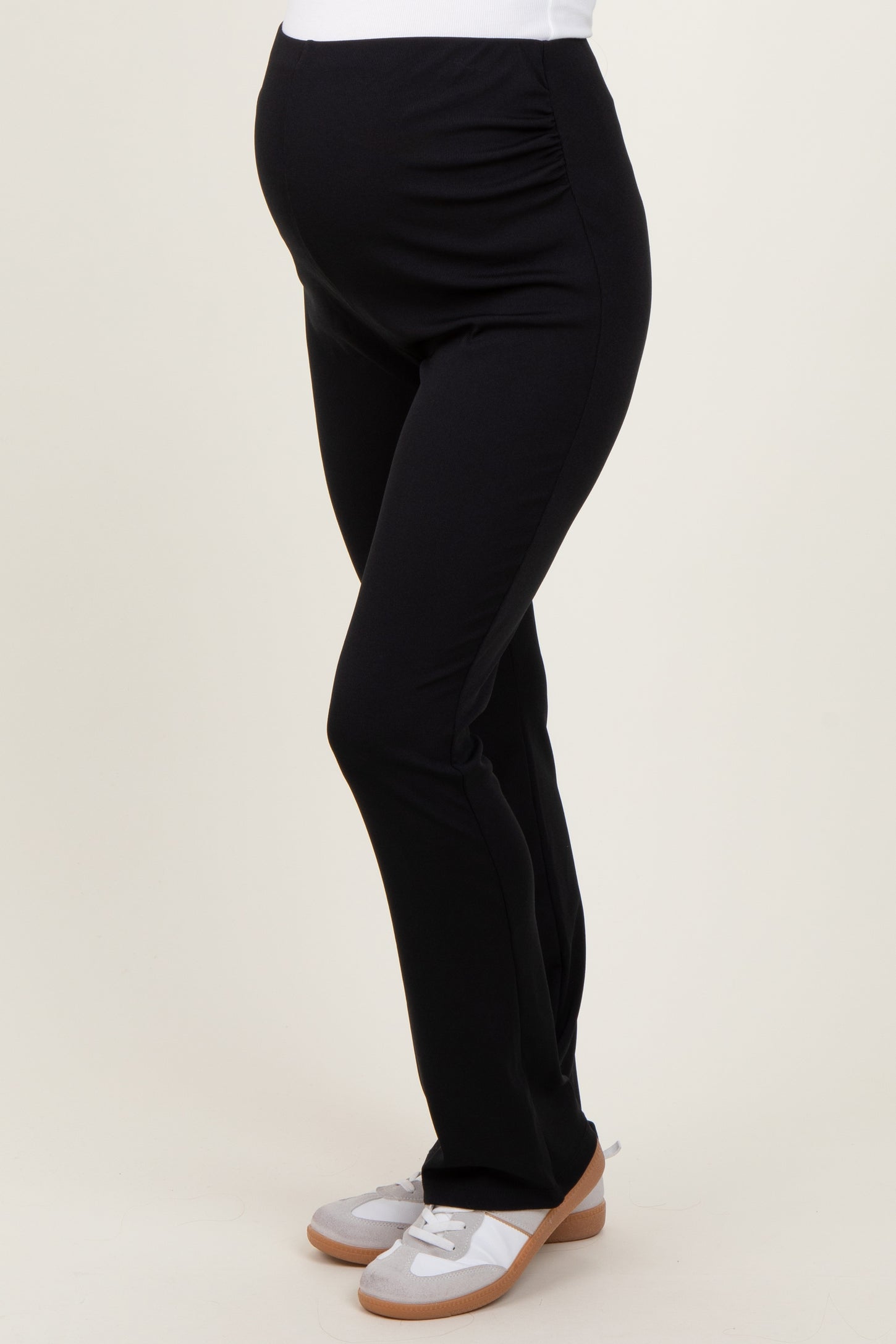woman wearing black maternity leggings, highlighting her baby bump, paired with casual slip-on shoes