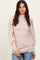 woman wearing a beige ribbed long sleeve mock neck top with puff sleeves and standing confidently against a neutral background