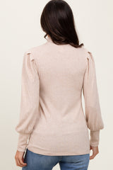 woman wearing a light beige ribbed sweater with puffed sleeves and a fitted silhouette, seen from the back