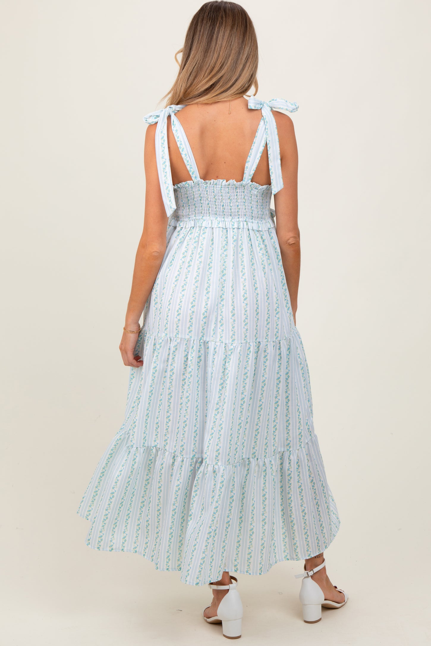 woman wearing a light blue maternity maxi dress with a smocked back and tie straps, showing a baby bump