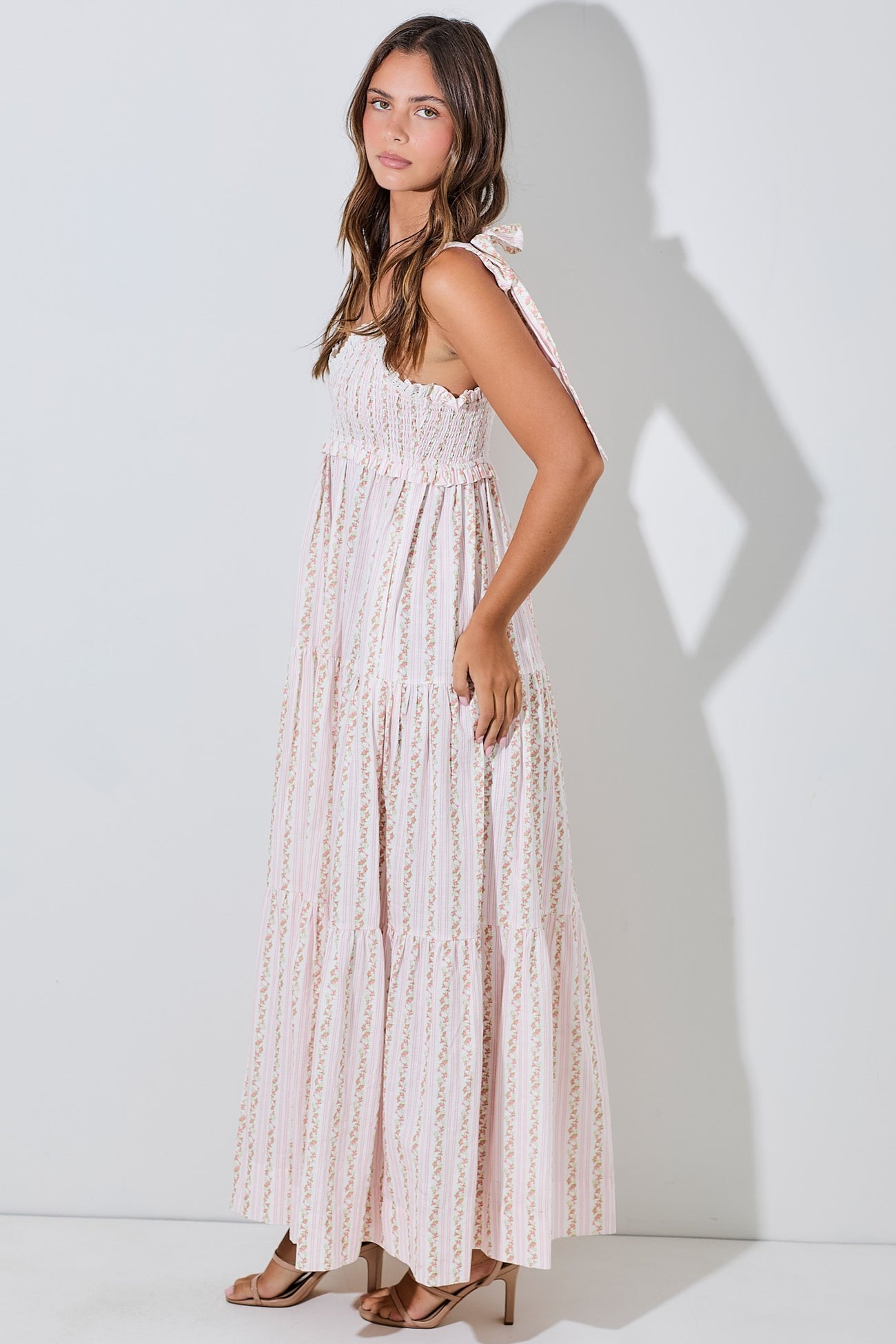 woman wearing a pink and white striped maxi dress with ruffled straps and a tiered skirt