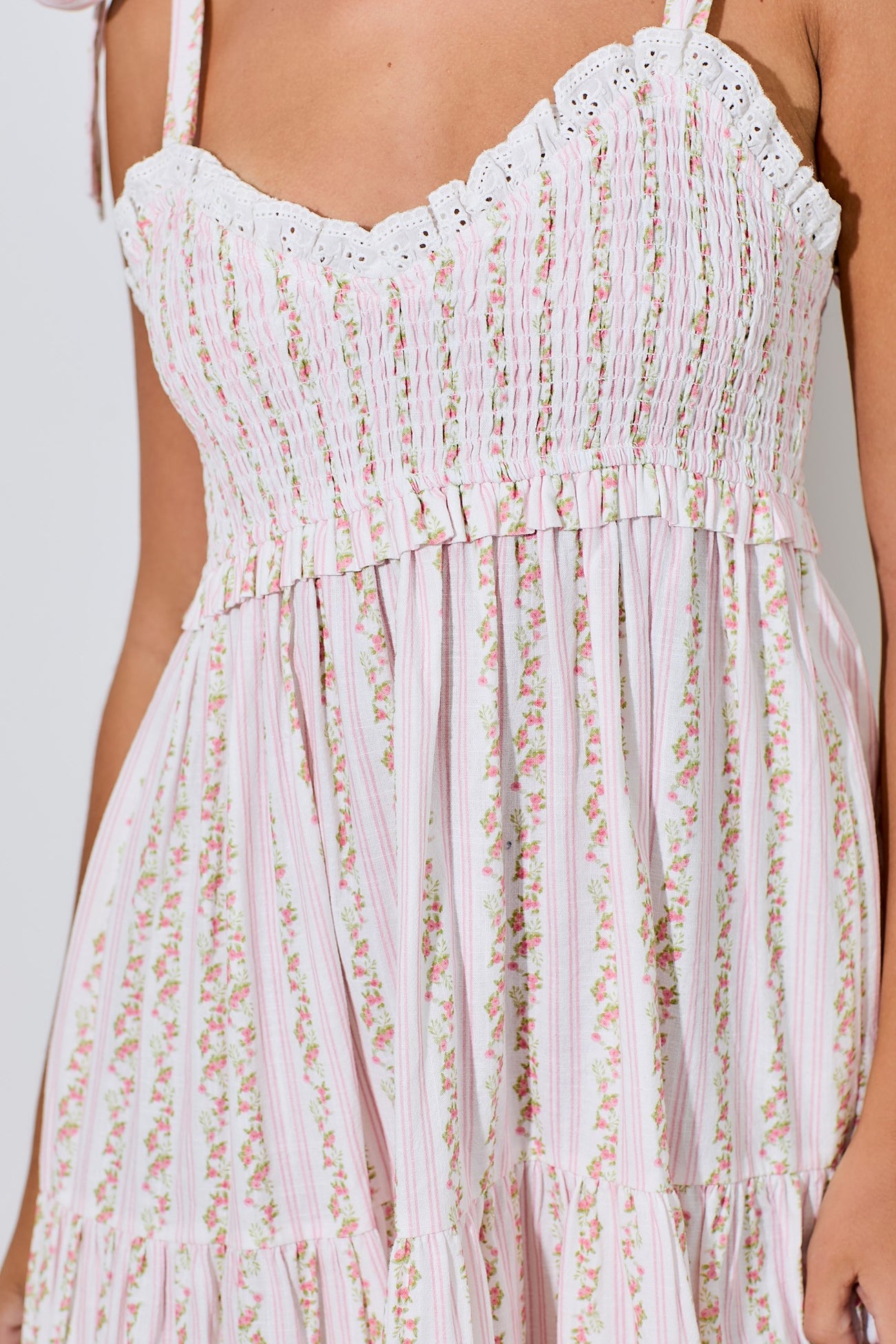 woman wearing a pink and white floral smocked maxi dress with lace trim and ruffled details