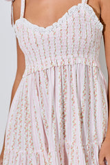 woman wearing a pink and white floral smocked maxi dress with lace trim and ruffled details