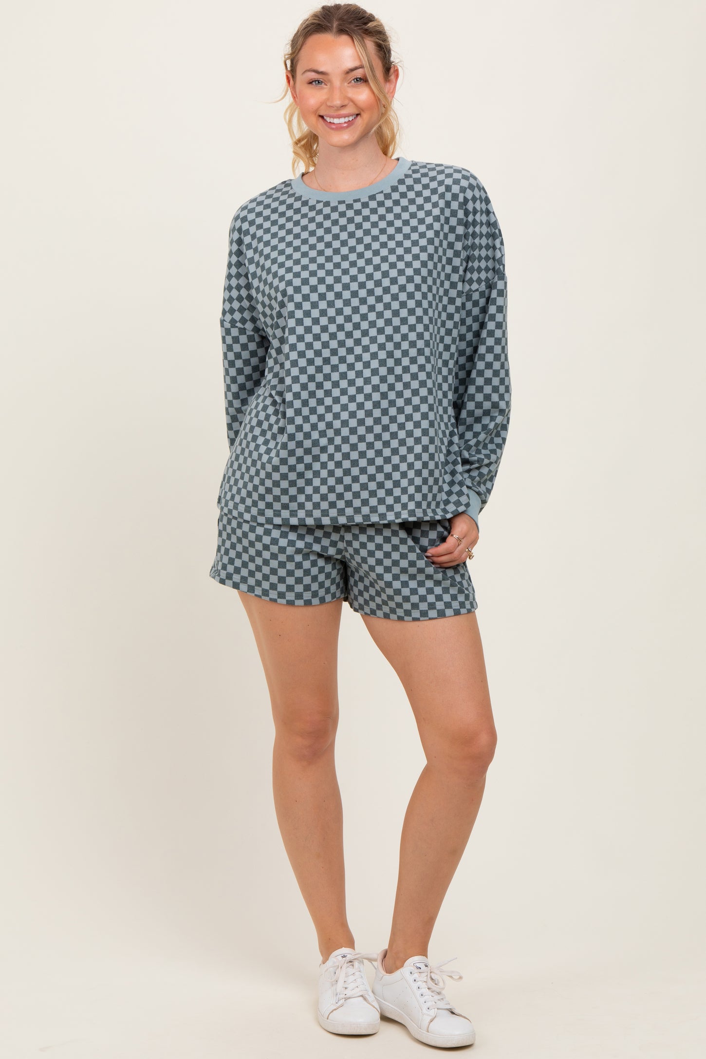 woman wearing a blue checkerboard print long sleeve top and matching shorts with white sneakers