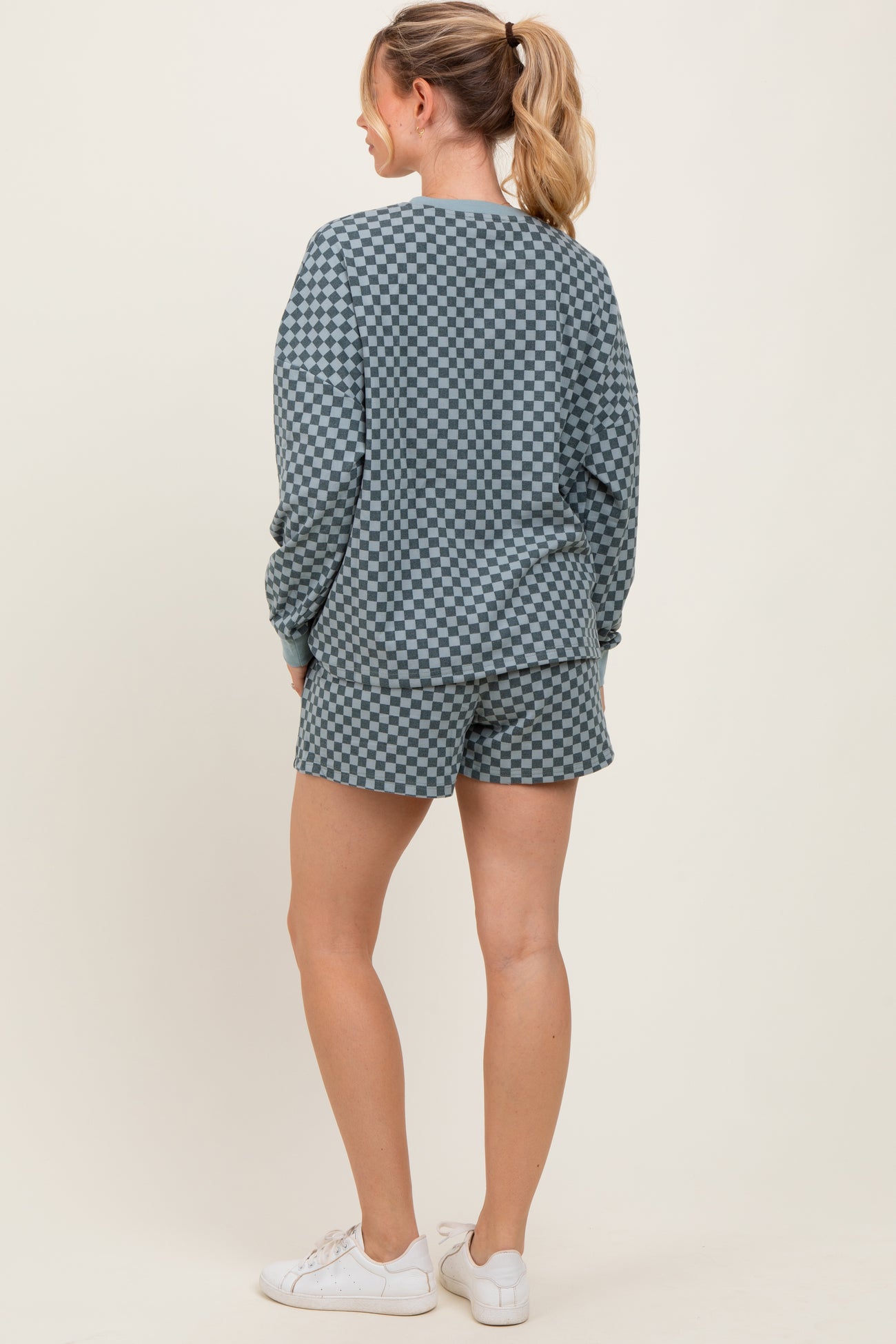 woman wearing a green checkered sweatshirt and matching shorts, standing with her back to the camera
