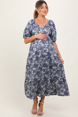 woman wearing a navy floral print maternity dress with puff sleeves and a baby bump visible