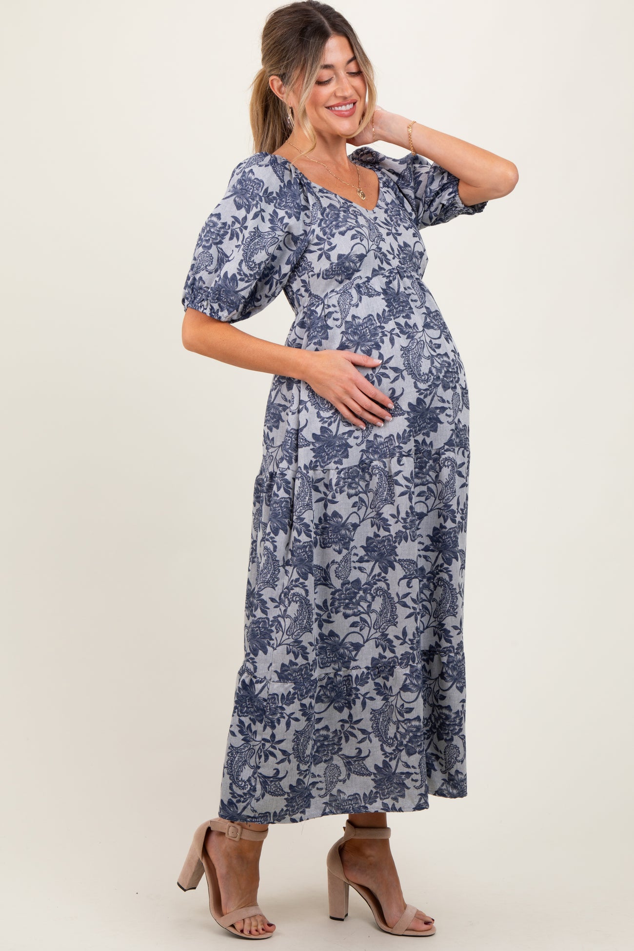 woman wearing a floral print blue maternity maxi dress and holding her baby bump