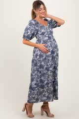 woman wearing a floral print blue maternity maxi dress and holding her baby bump