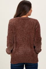 woman wearing a brown ribbed maternity sweater, seen from the back, paired with dark blue jeans