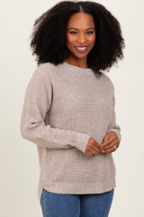 woman wearing a beige knit sweater with a relaxed fit and side slits, smiling at the camera