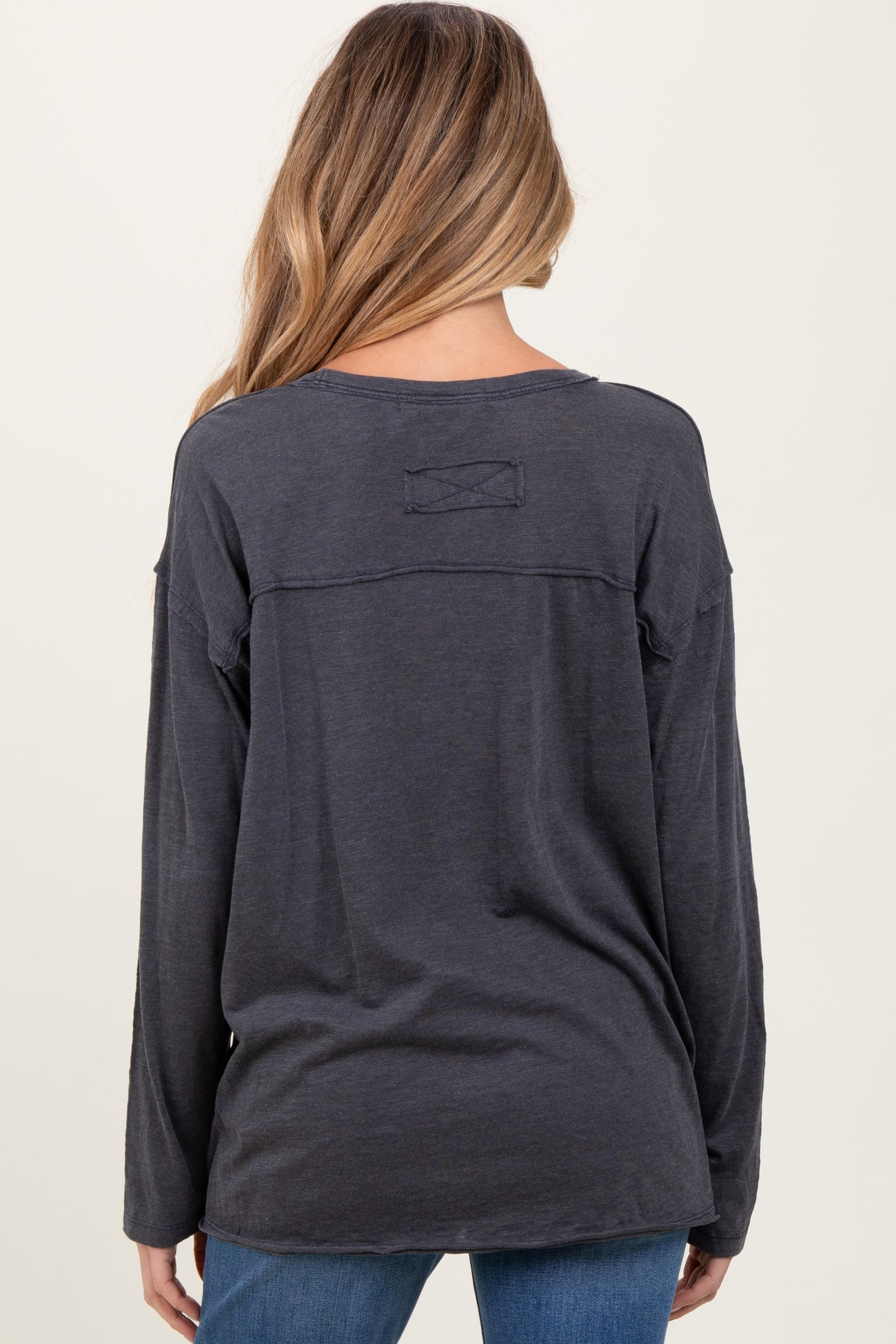 woman wearing a dark gray long sleeve maternity top, view from the back with a relaxed fit and unique seam detail