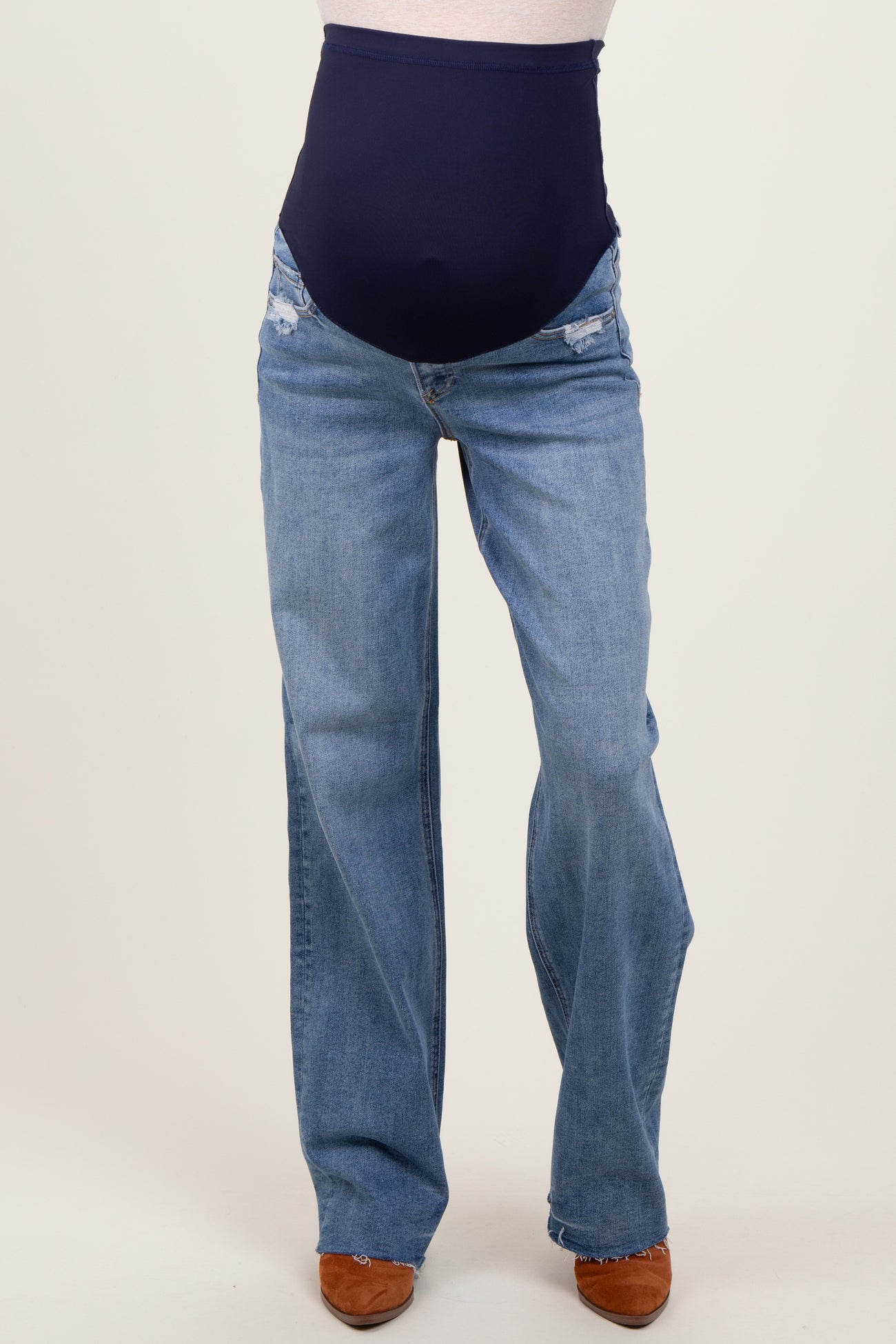 woman wearing distressed light blue maternity jeans with a dark navy over-the-bump waistband