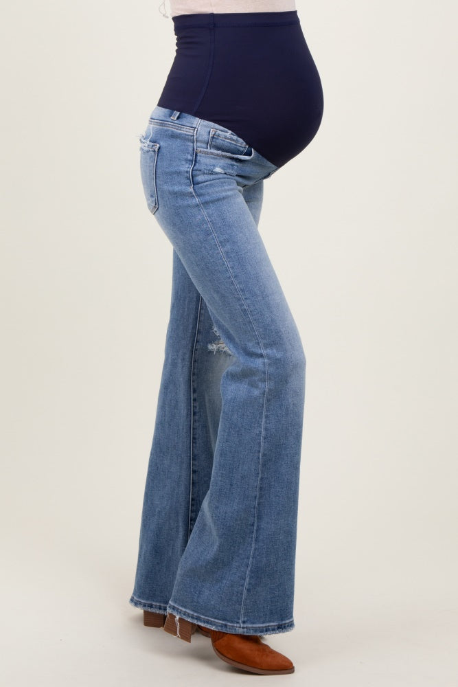 woman wearing a navy blue maternity belly band with flared light wash maternity jeans and a visible baby bump