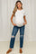 woman wearing a white short sleeve maternity top and distressed blue jeans, showing her baby bump