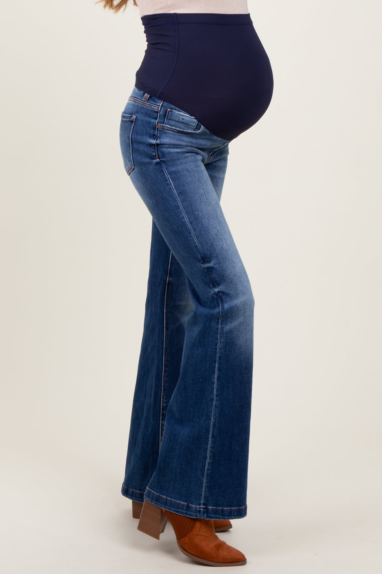woman wearing a navy blue maternity belly band with flared jeans and showing her baby bump