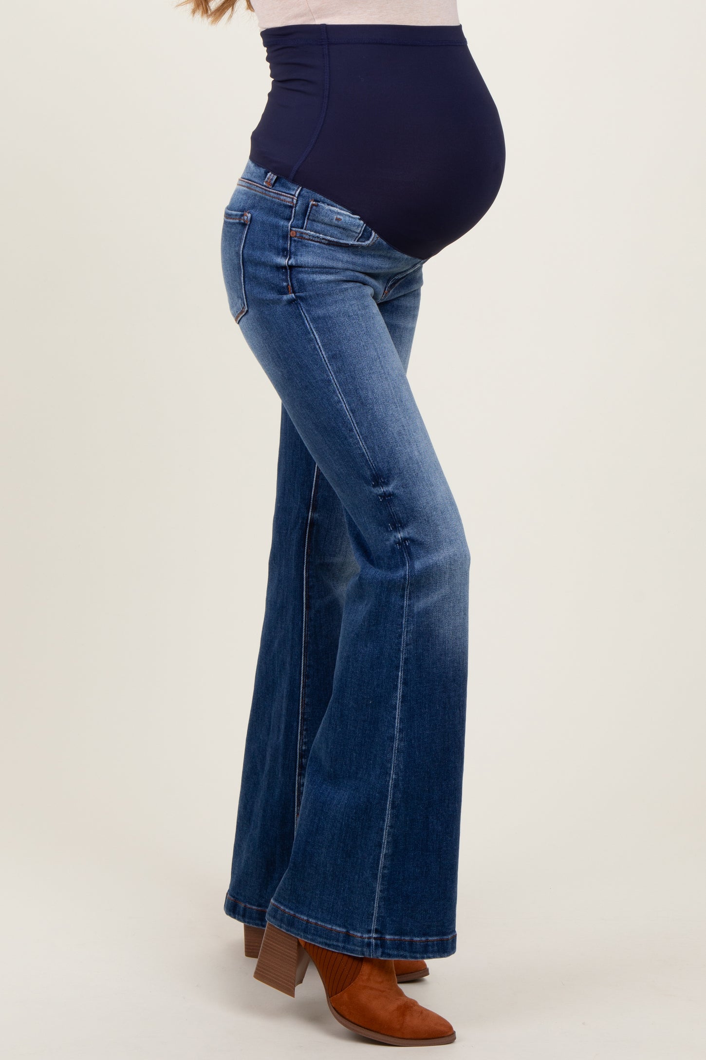 woman wearing a navy blue maternity belly band with flared jeans and showing her baby bump