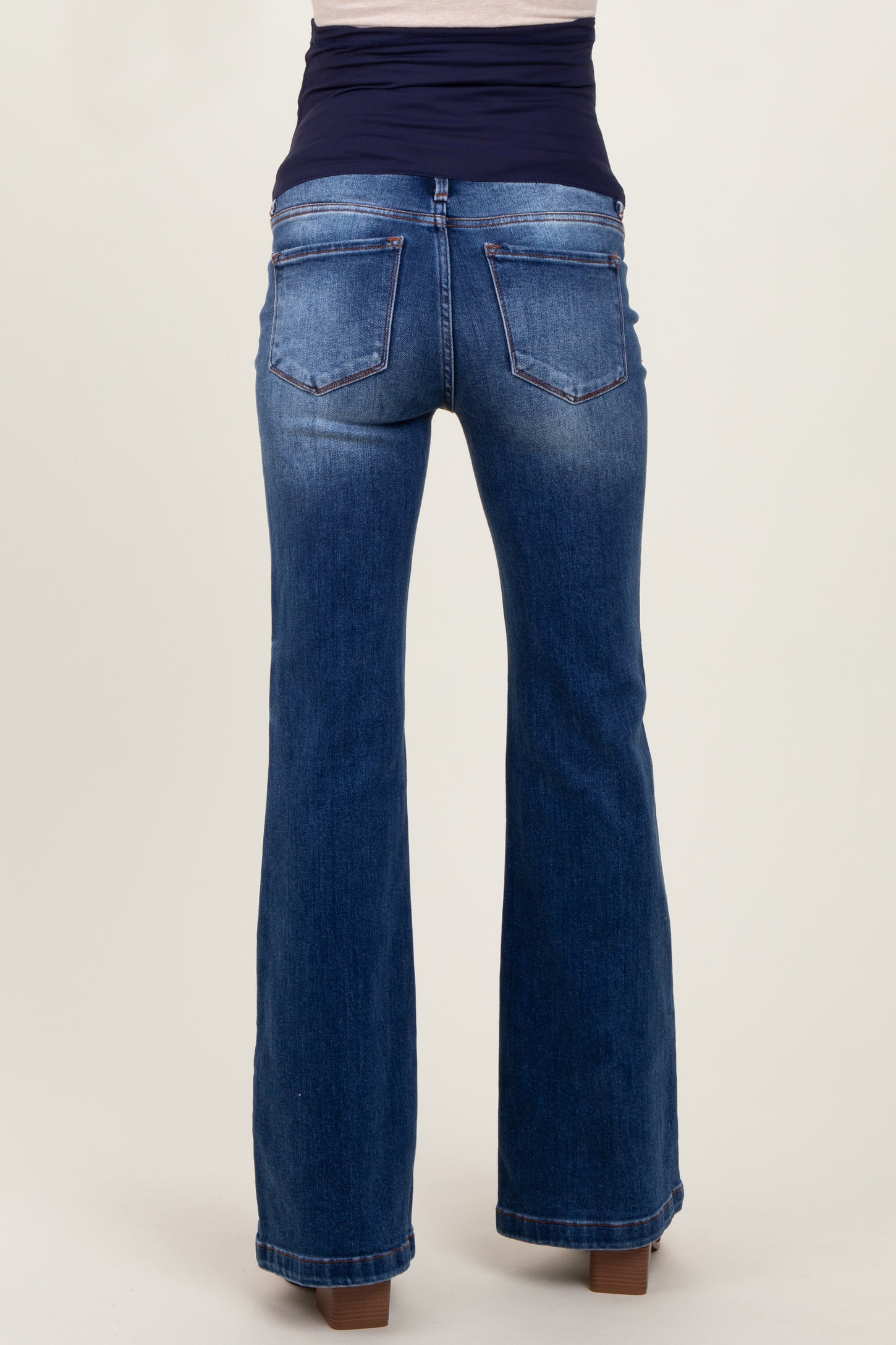 woman wearing dark blue bootcut maternity jeans, with a black belly band for support