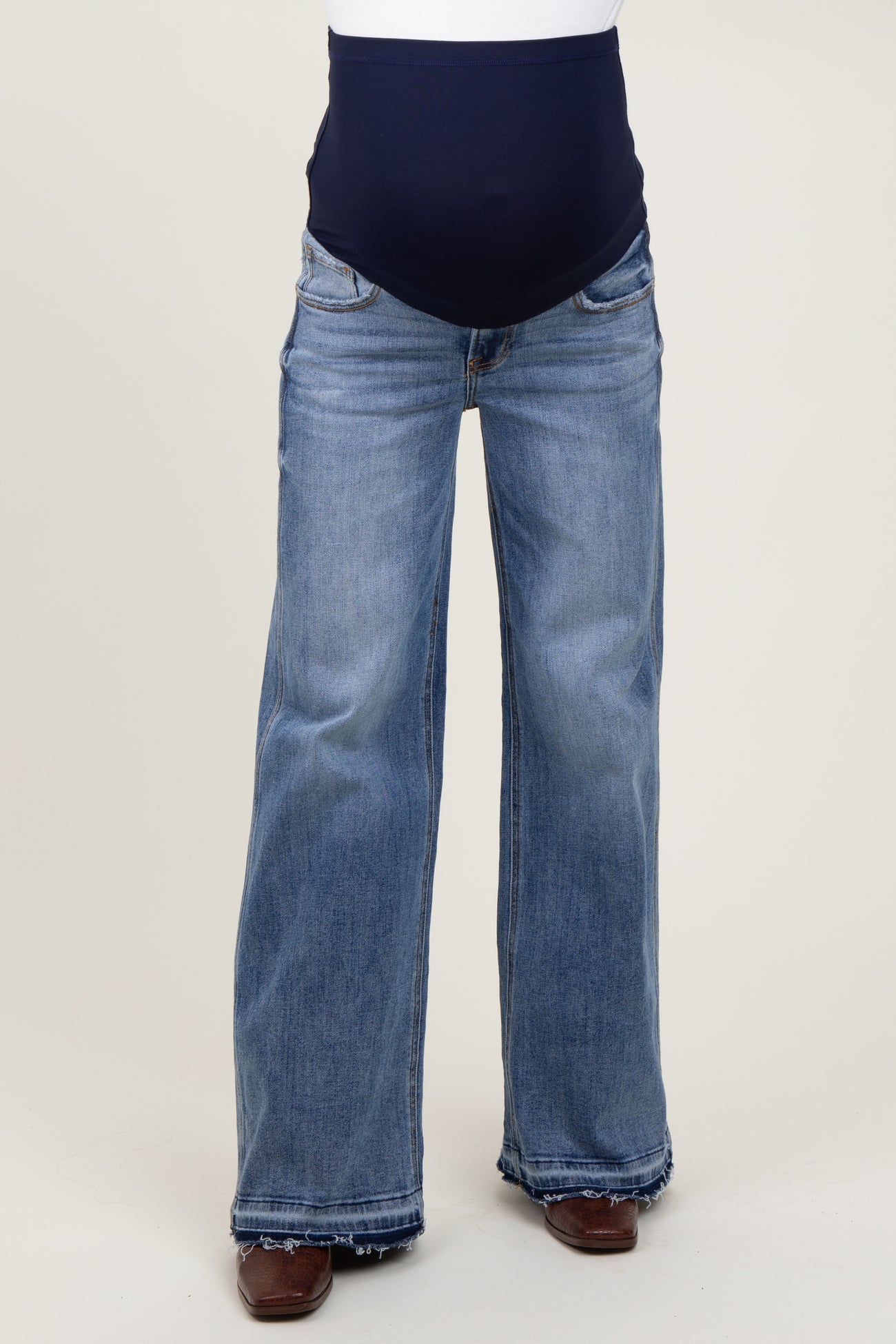 woman wearing a pair of light blue maternity flared jeans with a navy blue over-the-bump waistband