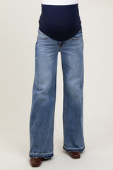 woman wearing a pair of light blue maternity flared jeans with a navy blue over-the-bump waistband