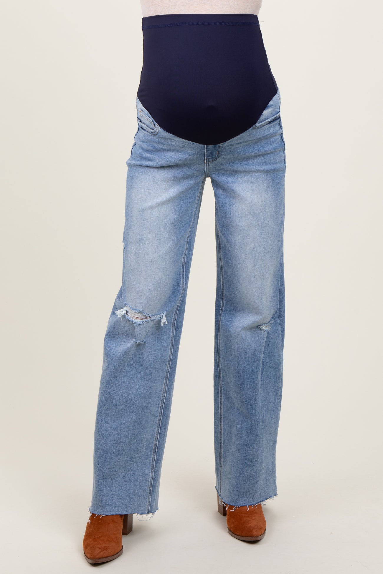 woman wearing distressed light blue maternity jeans with a navy blue over-the-bump waistband