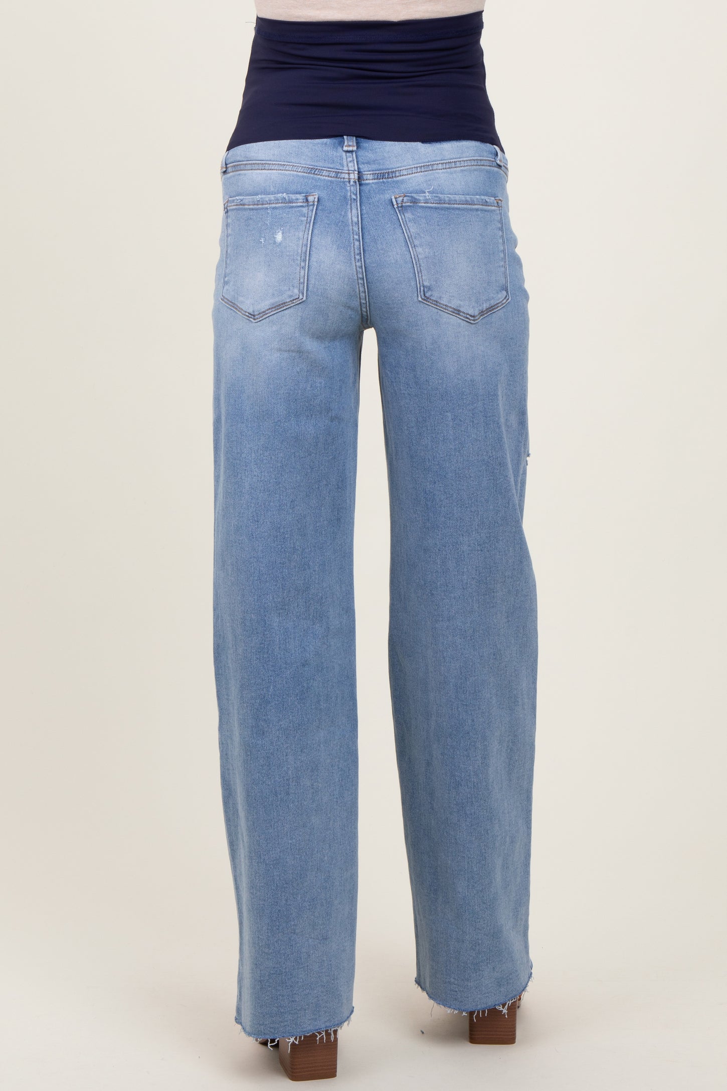 woman wearing light blue maternity jeans with a wide-leg fit and frayed hem, showing the back view