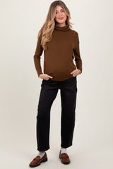 woman wearing a brown maternity turtleneck top and black relaxed fit pants with a visible baby bump