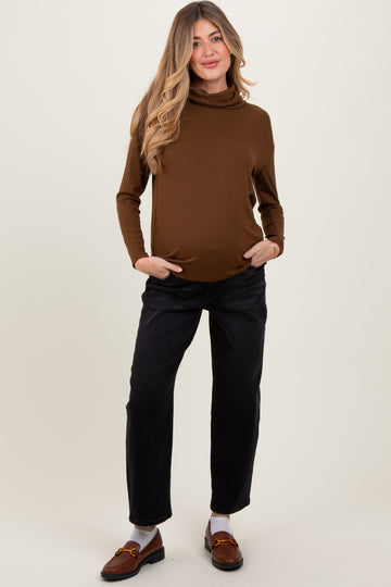 woman wearing a brown maternity turtleneck top and black relaxed fit pants with a visible baby bump