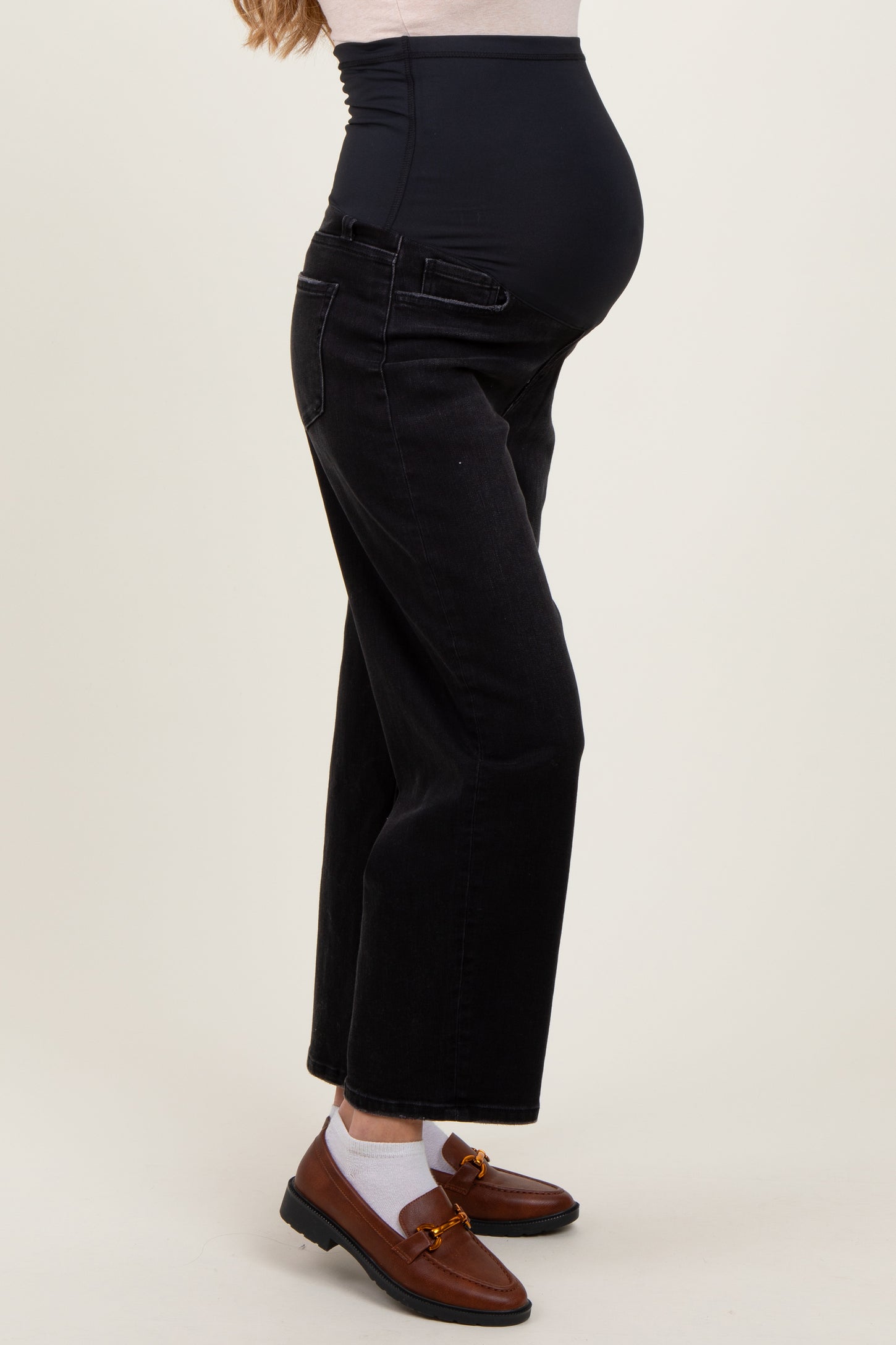 woman wearing black maternity jeans with a high waistband and a visible baby bump