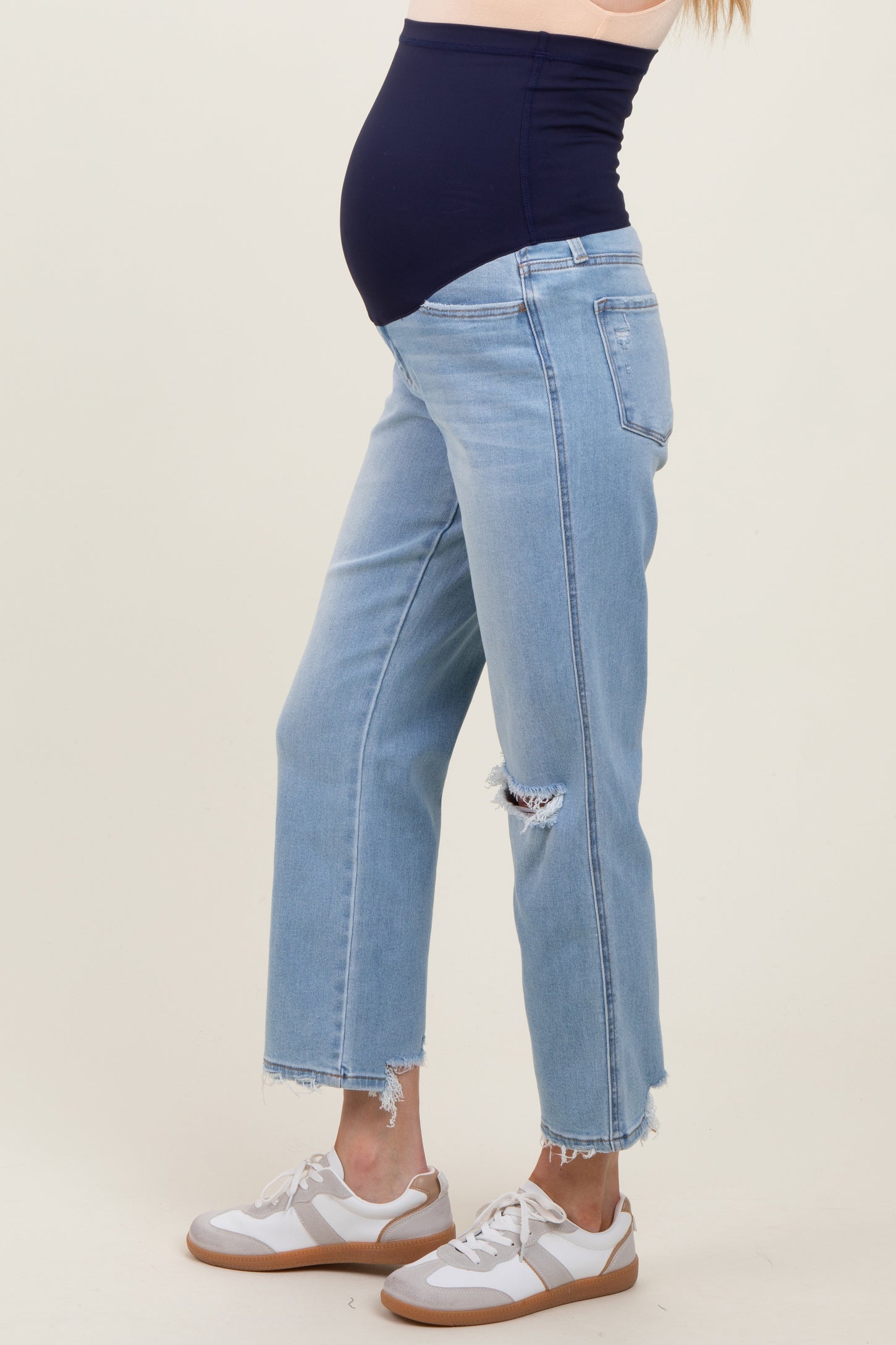 maternity wear light blue distressed jeans with a black maternity belly band and model showing her baby bump