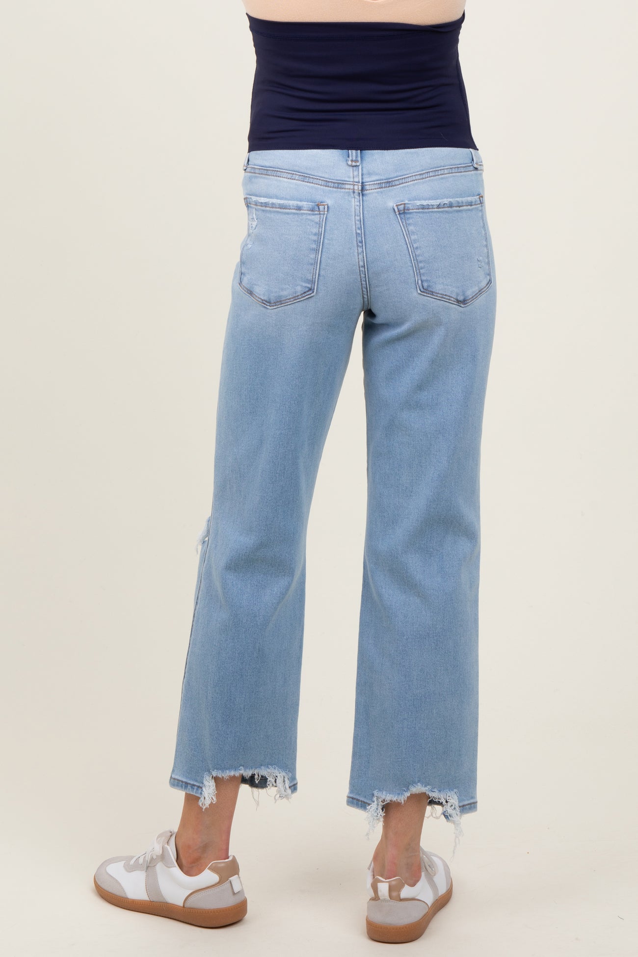woman wearing light blue maternity cropped jeans with frayed hems, showing a relaxed fit from the back