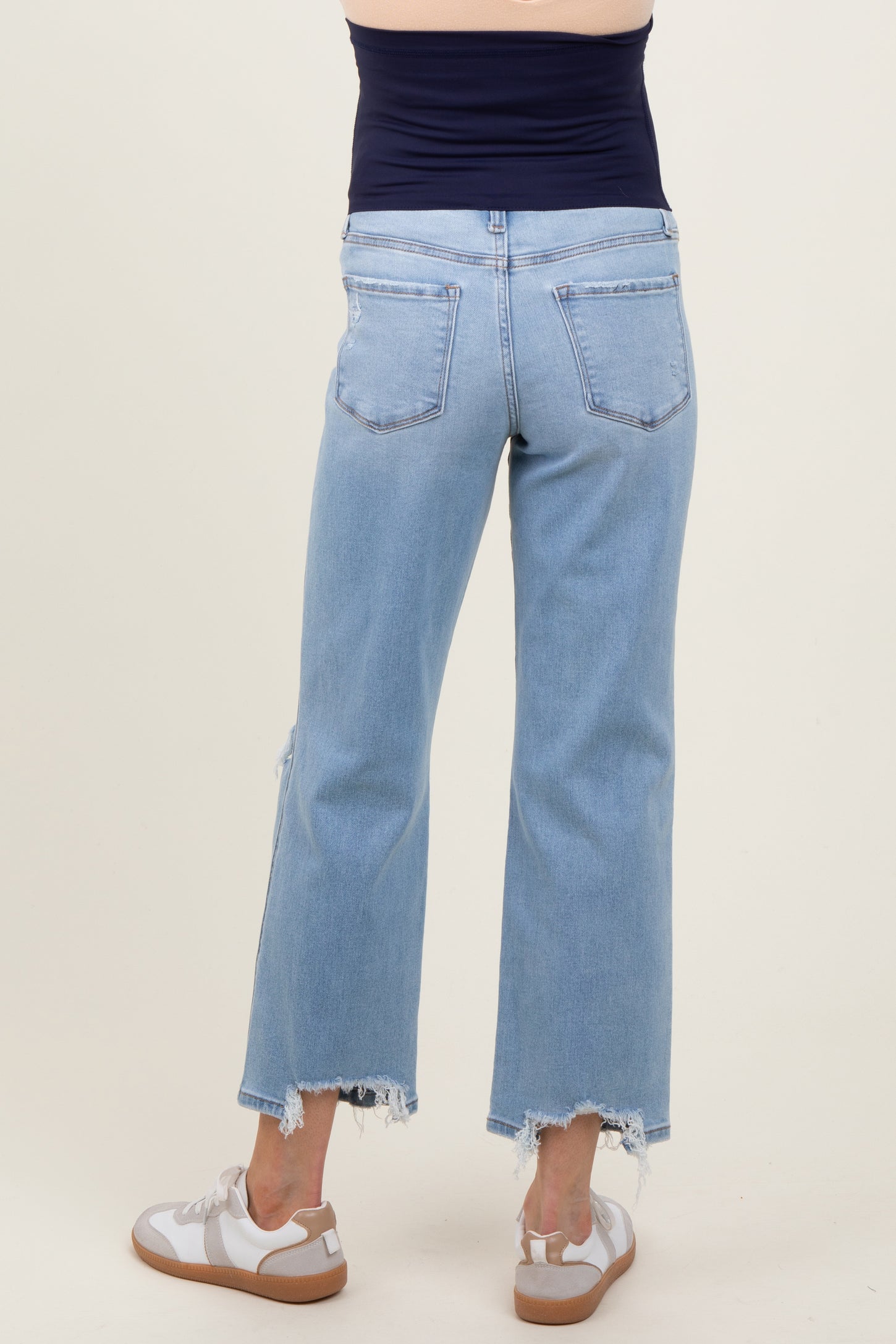 woman wearing light blue maternity cropped jeans with frayed hems, showing a relaxed fit from the back