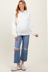 woman wearing a white maternity hoodie with a relaxed fit and light wash distressed denim jeans, showing her baby bump