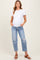 woman wearing a white short sleeve maternity top and distressed light blue maternity jeans, showing her baby bump