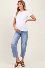 woman wearing a white short sleeve maternity top and distressed blue jeans, holding her baby bump