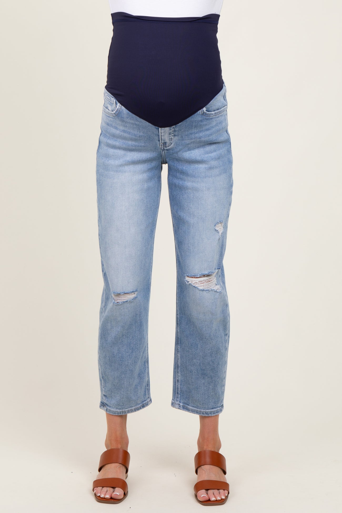 woman wearing a navy blue maternity belly support jeans with distressed detailing and light wash denim