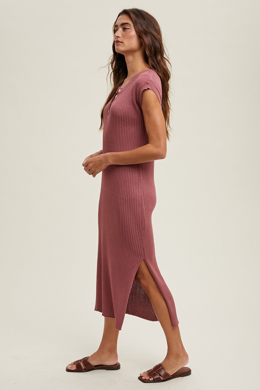 woman wearing a dusty rose ribbed midi dress with short sleeves and side slits, styled with brown slip-on sandals