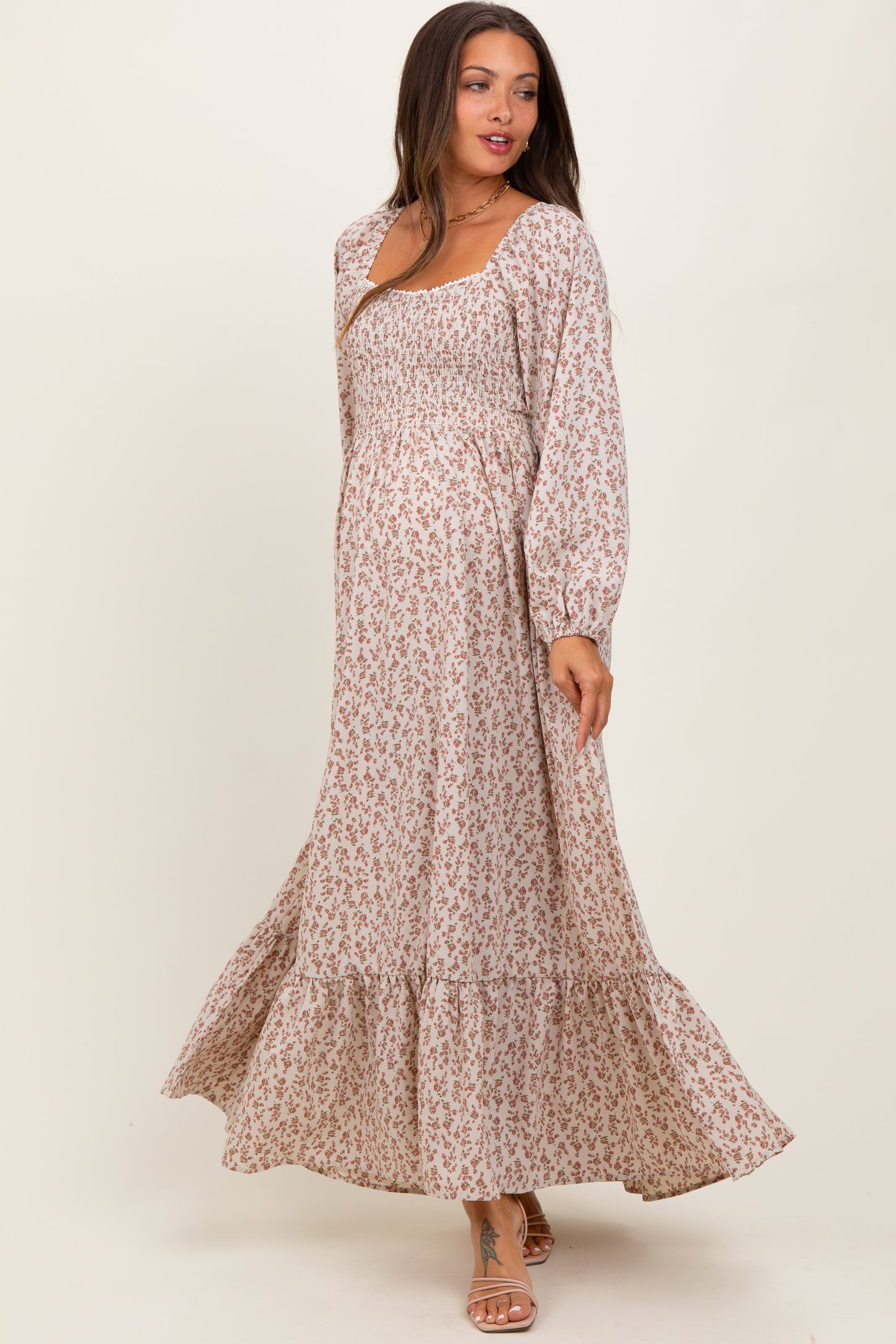 woman wearing a flowy floral print maternity maxi dress with long sleeves and a baby bump visible