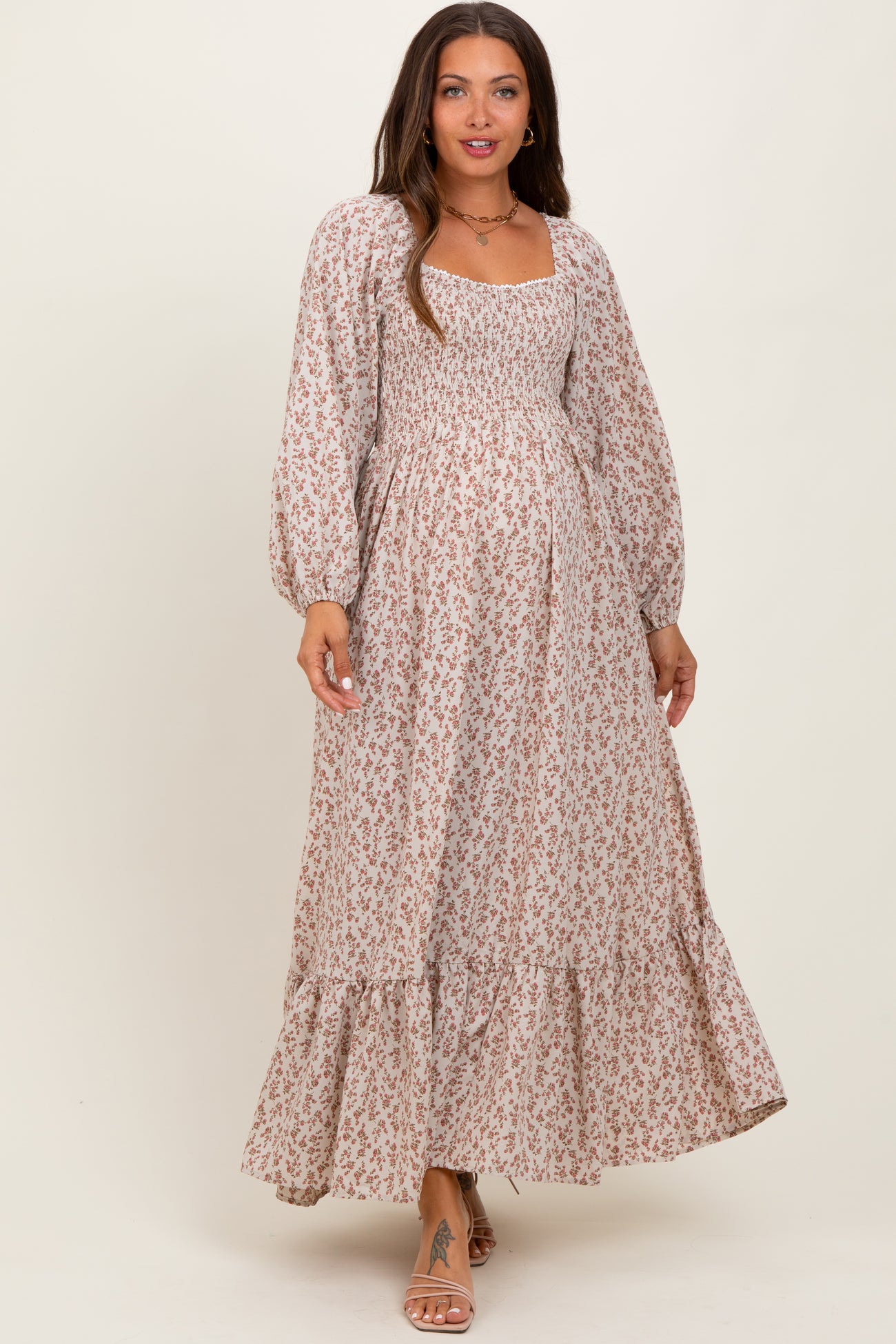 woman wearing a floral print maternity maxi dress with long sleeves and a smocked bodice, showcasing a baby bump