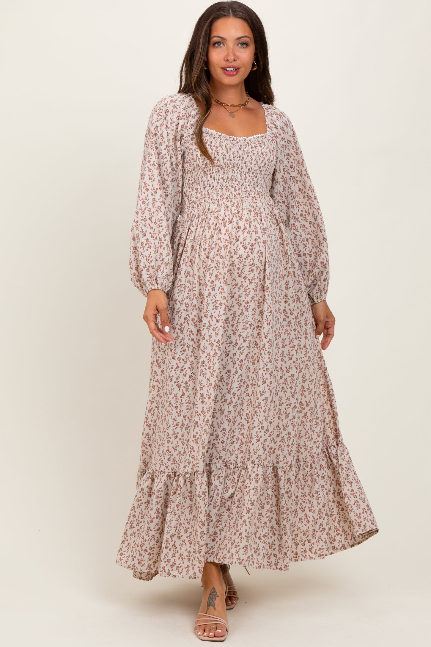 woman wearing a floral print maternity maxi dress with long sleeves and a smocked bodice, showcasing a baby bump