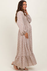 woman wearing a floral long sleeve maternity dress with a tiered skirt and holding her baby bump