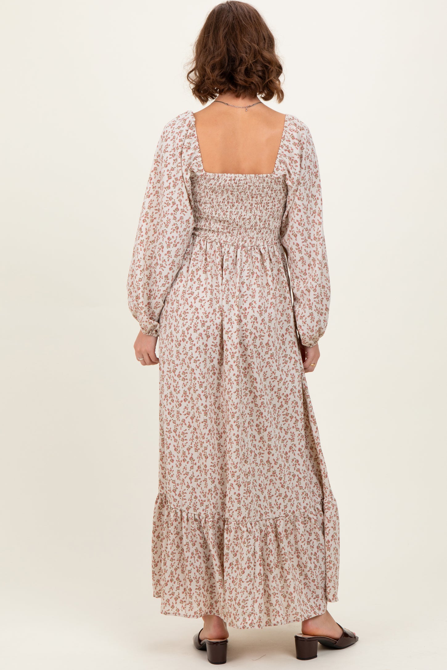 woman wearing a floral long sleeve maxi dress with a square back and gathered waist, shown from the back