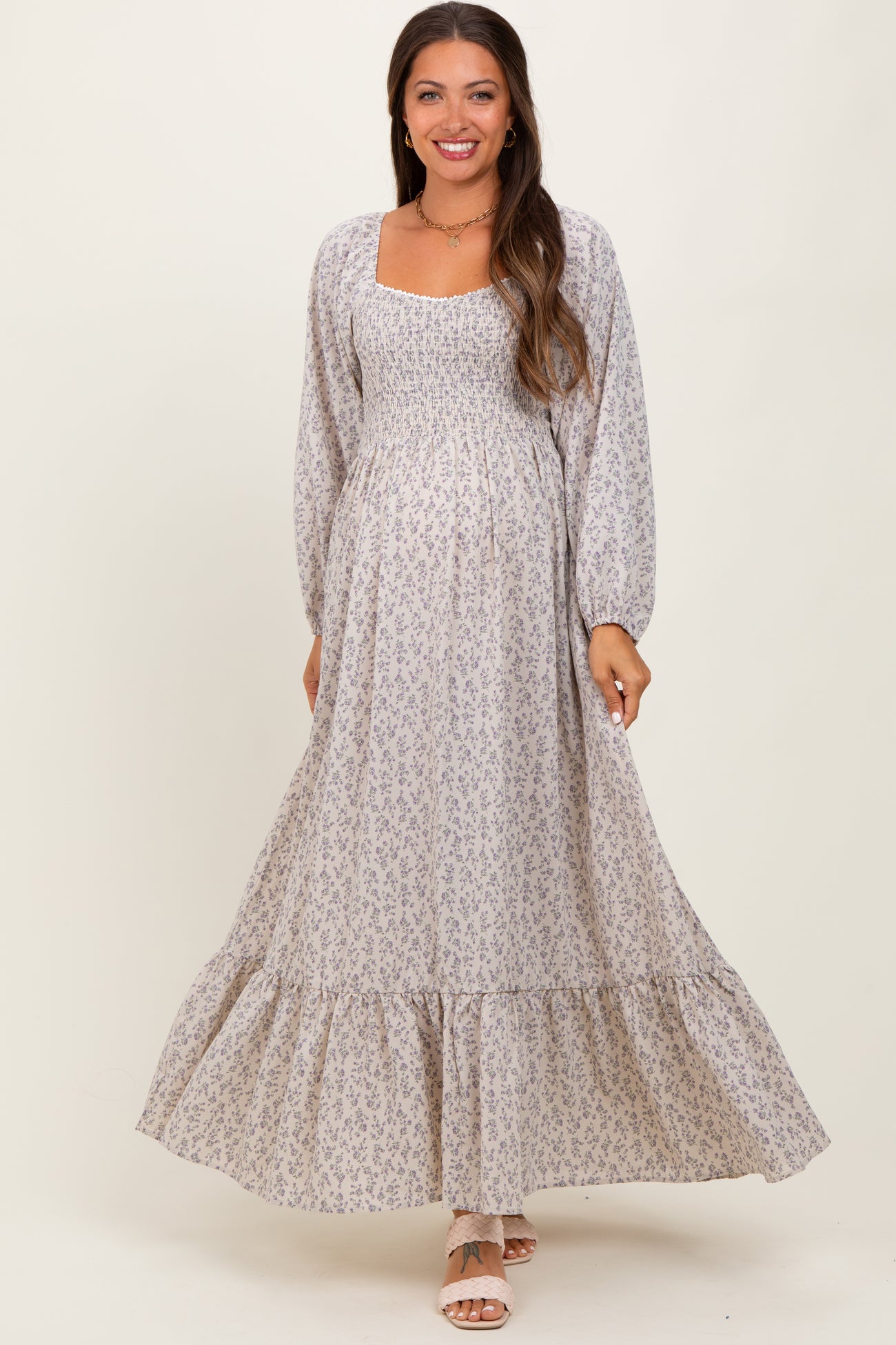 woman wearing a light purple floral maternity maxi dress with long sleeves and a smocked bodice, showing her baby bump