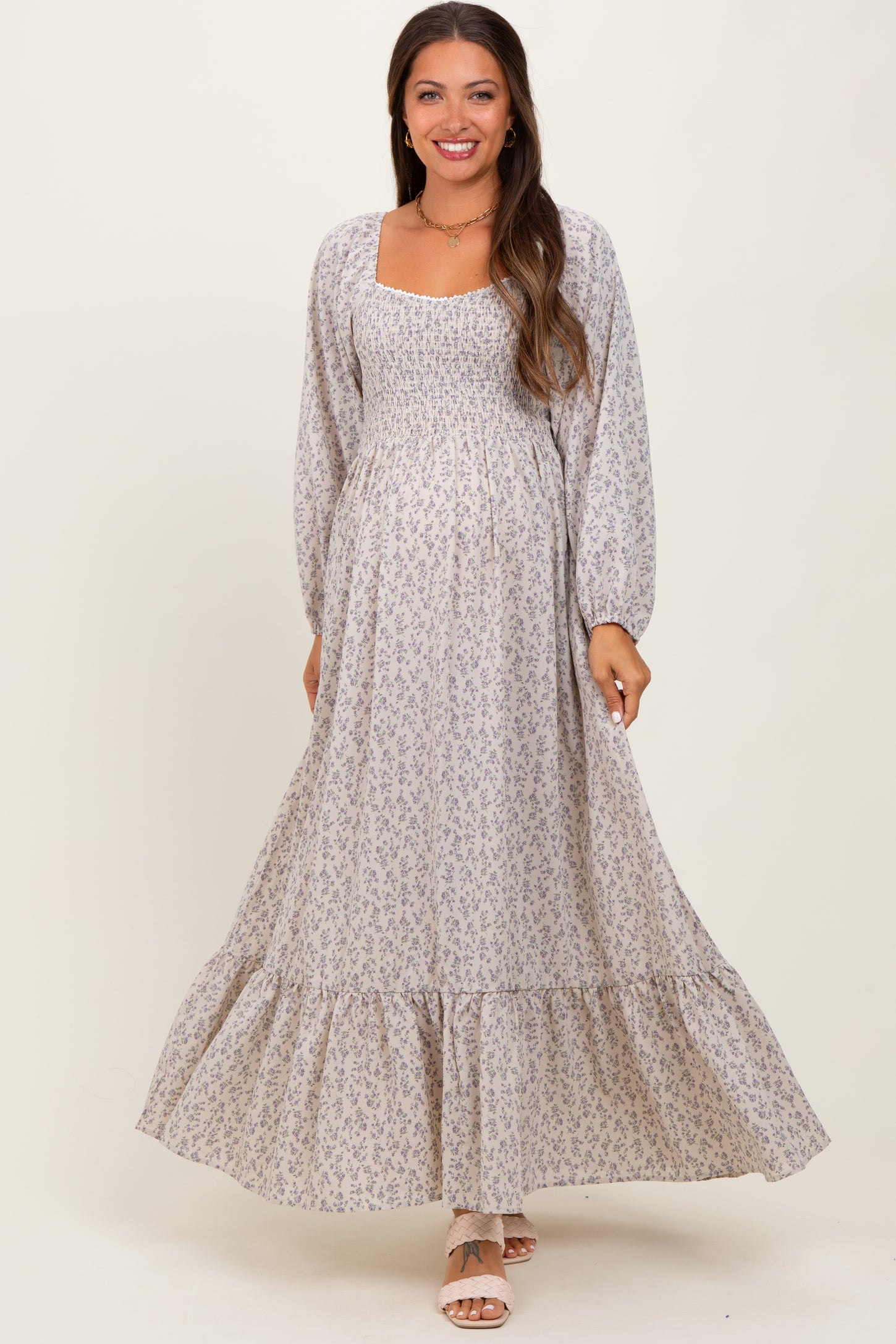 woman wearing a light purple floral maternity maxi dress with long sleeves and a smocked bodice, showing her baby bump