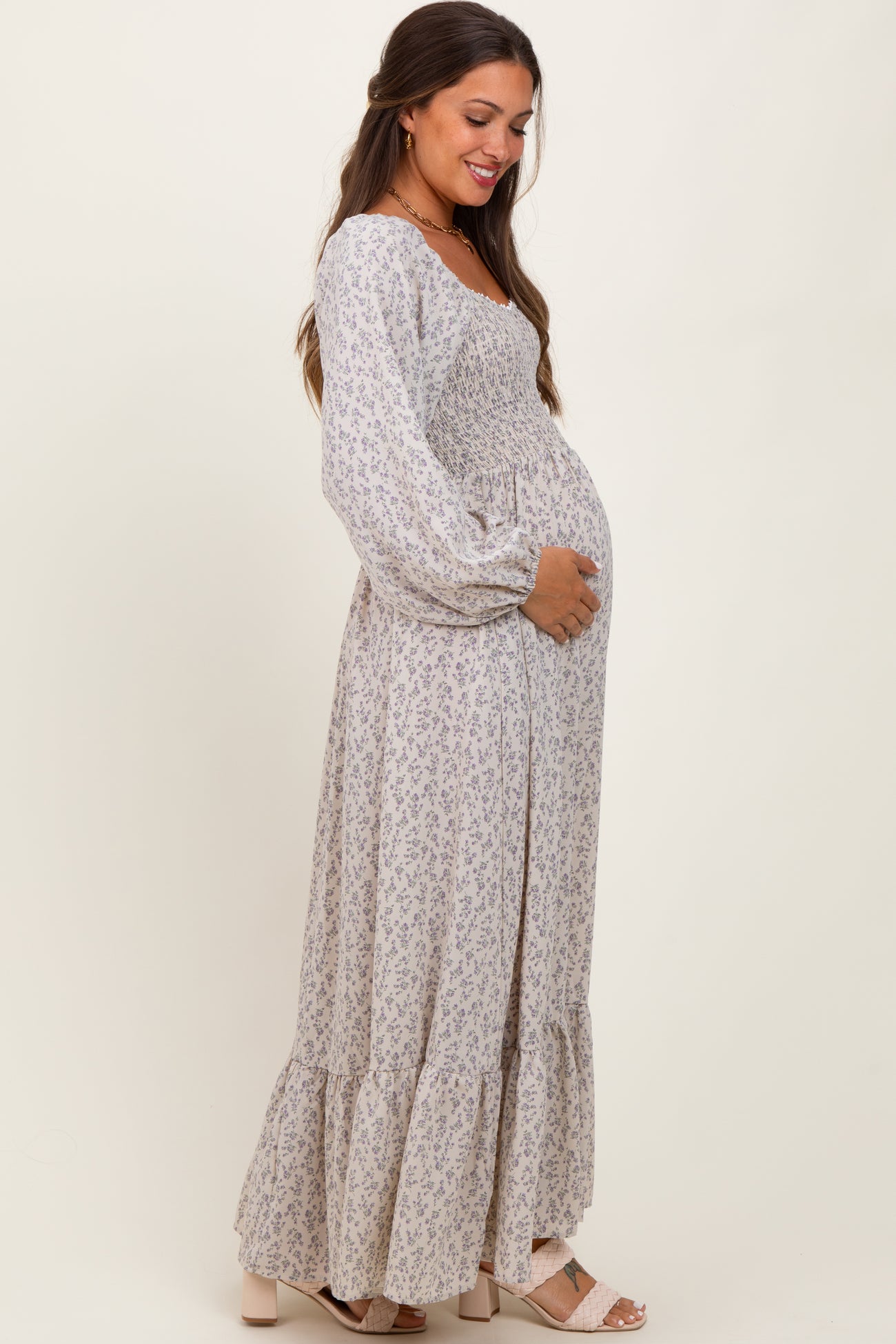 woman wearing a floral print long sleeve maternity dress and holding her baby bump