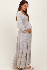 woman wearing a floral print long sleeve maternity dress and holding her baby bump