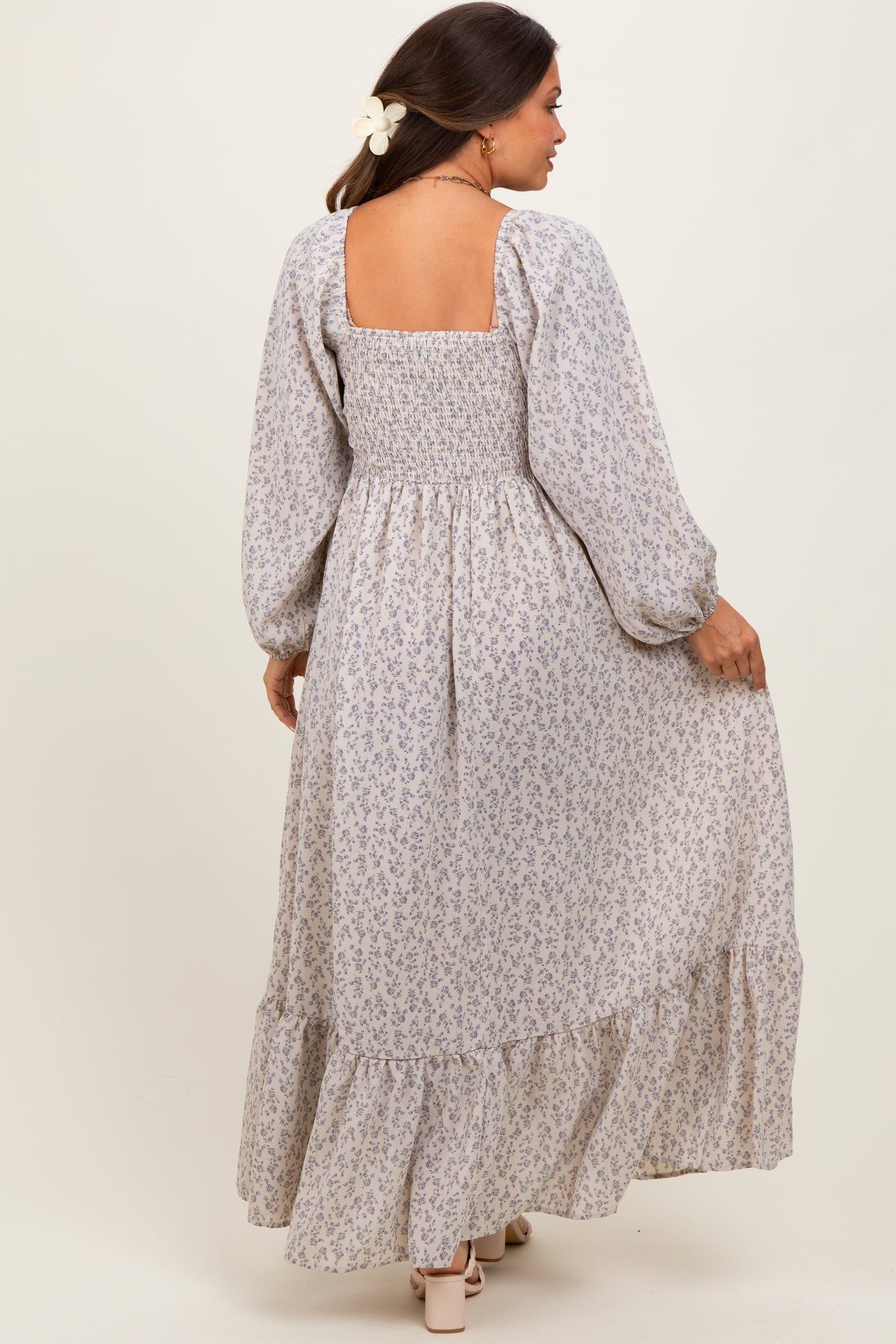 woman wearing a long sleeve floral maternity maxi dress with a smocked bodice and tiered skirt, showing a baby bump
