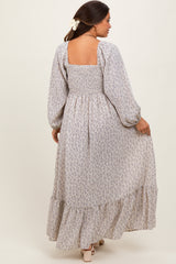 woman wearing a long sleeve floral maternity maxi dress with a smocked bodice and tiered skirt, showing a baby bump
